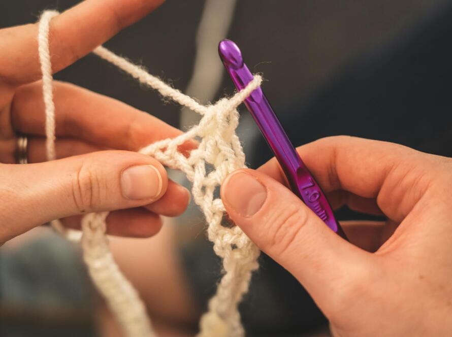 Person Holding Purple Crochet Hook And White Yarn