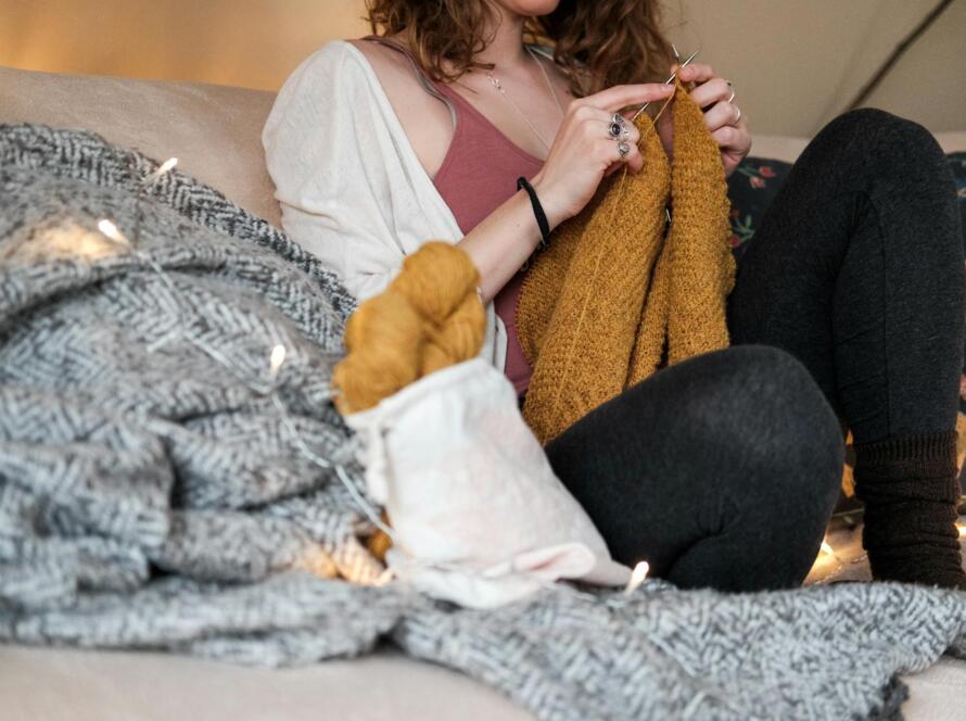 Woman Sitting On A Sofa While Knitting A Sweater